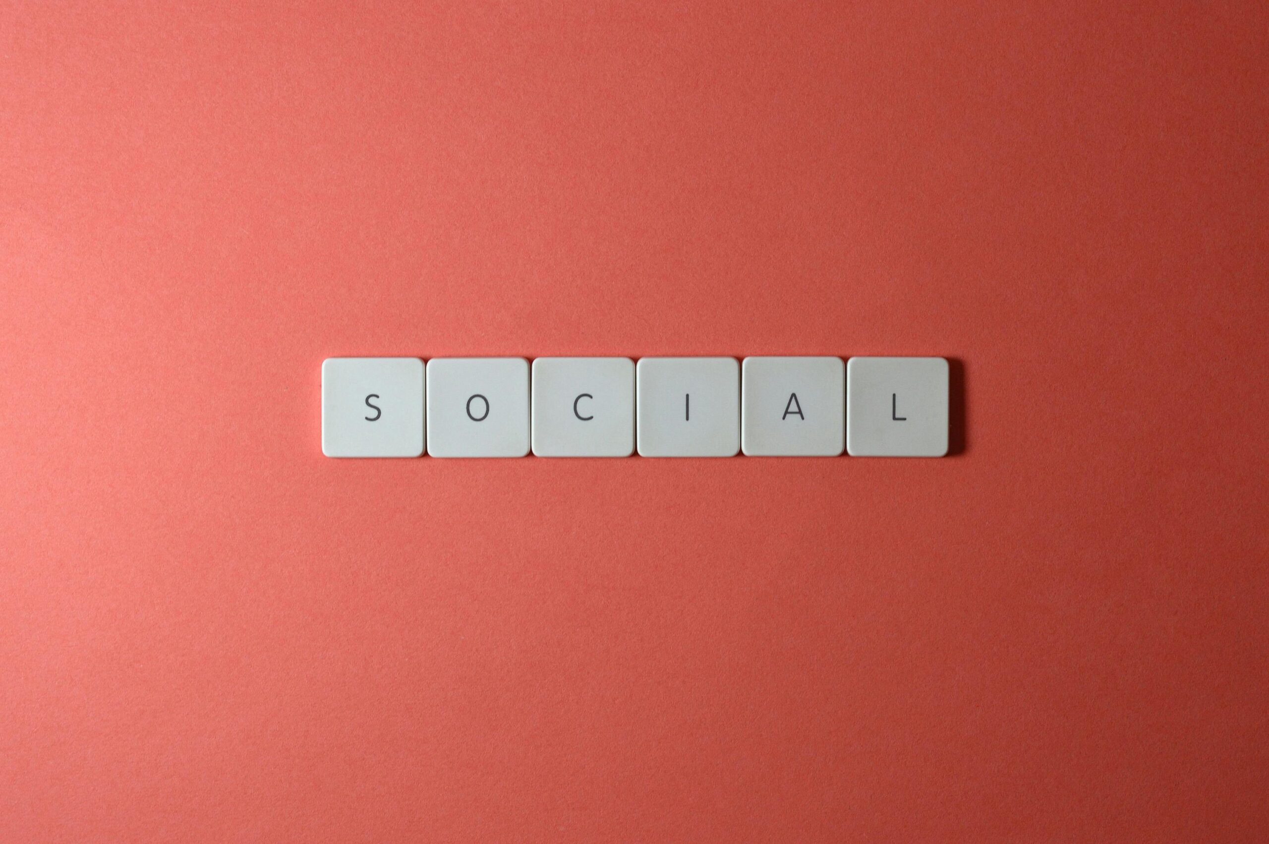 Close-up of the word 'SOCIAL' formed with tiles on a red surface, offering copyspace.