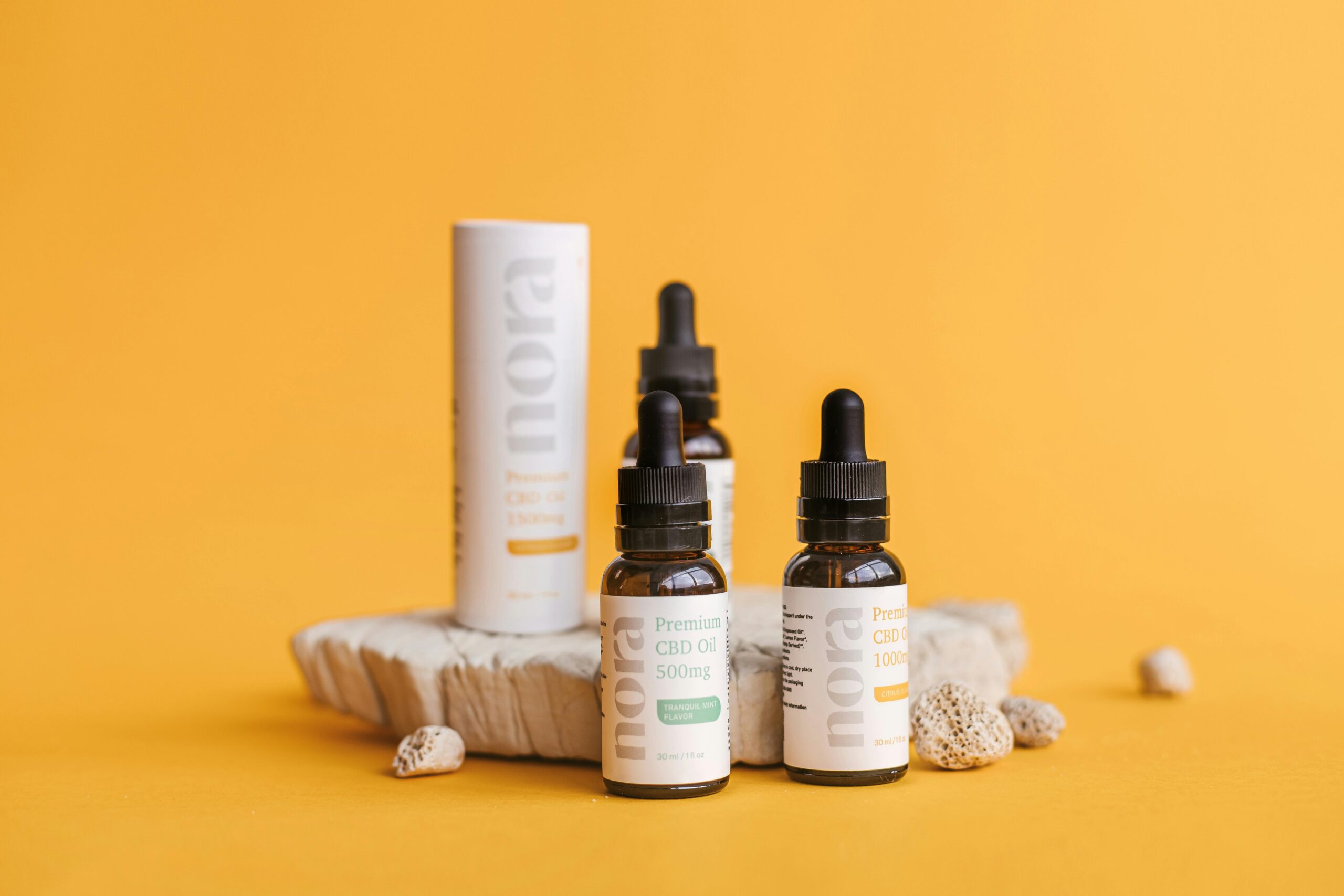 Stylish product shot of CBD oil bottles with packaging on a yellow background highlighting modern design.