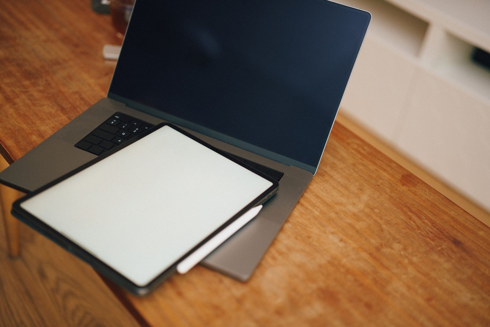 Open laptop with a graphic tablet on a wooden desk, perfect for design and digital workspaces.
