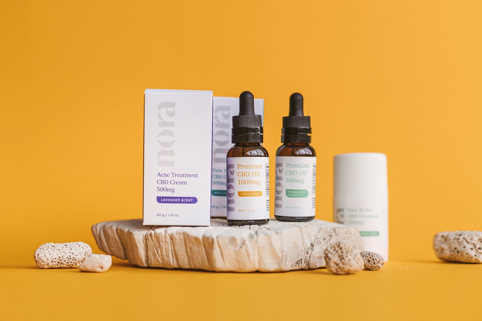 Close-up of CBD oil bottles and cream on a yellow background with natural textures.
