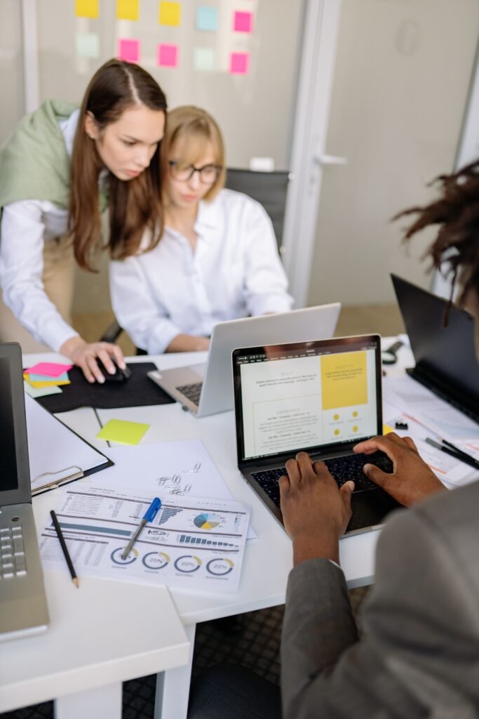 Colleagues collaborating in a modern office setting with laptops and documents.