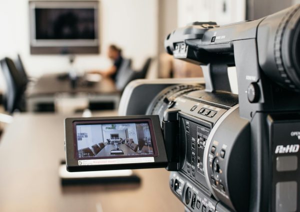 Close-up of professional video camera recording in modern office environment.