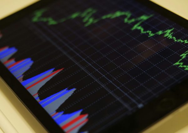 Close-up of a tablet displaying stock market analysis with colorful graphs.
