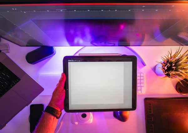 A vibrant workspace featuring a digital tablet and neon lighting, ideal for designers or photographers.